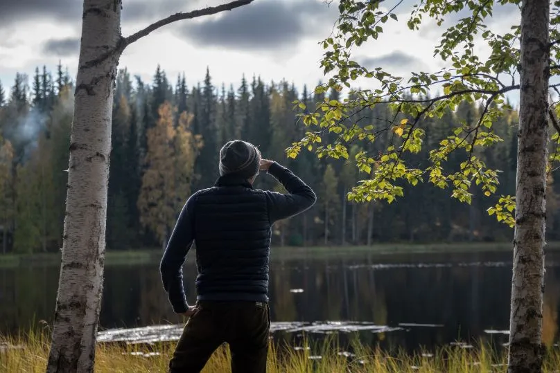 Man die in de verte kijkt aan de rand van een meer Finland