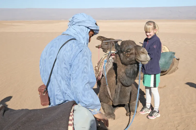 Meisje aait een kameel in Marokkaanse woestijn
