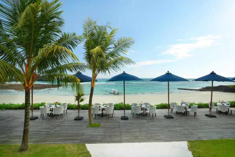 Terras aan strand met palmbomen en parasols