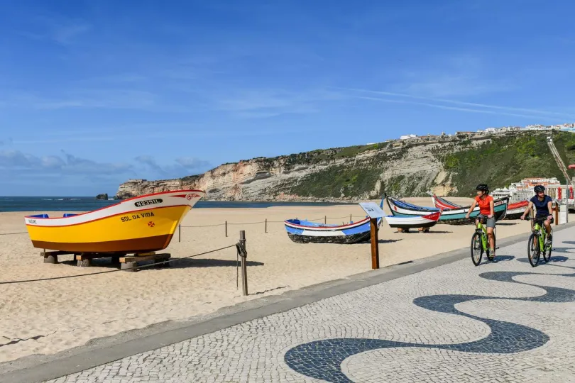 Twee mensen fietsen langs het strand van Nazare.
