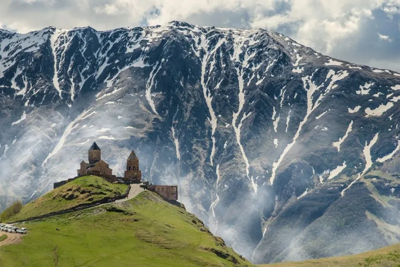 Roadtrip Georgië - een kerk op een heuvel met bergen in Kazbegi.