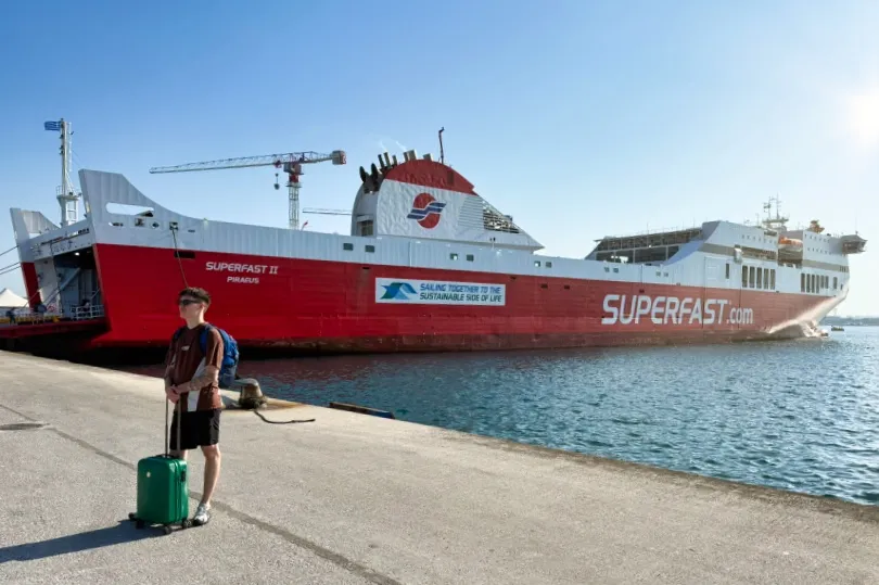 Een jongeman wacht met een koffer op de ferry naar Griekenland.