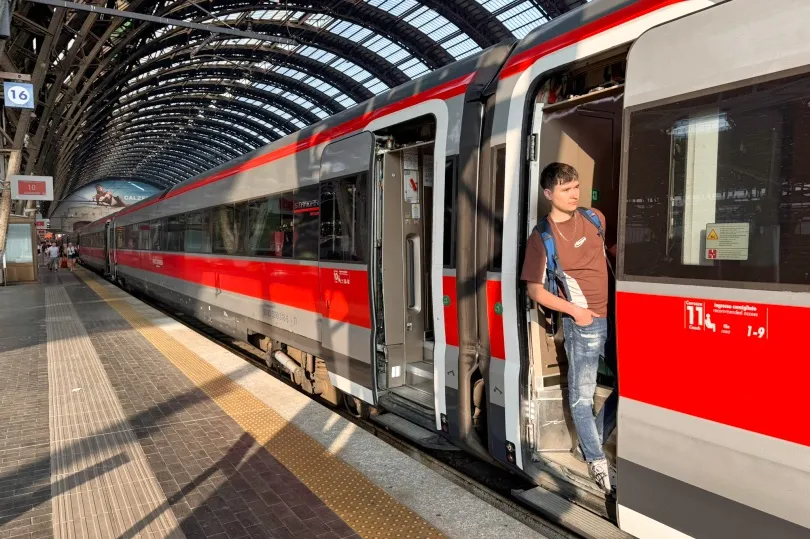 Jongeman staat in de deuropening van een trein op station Milaan.