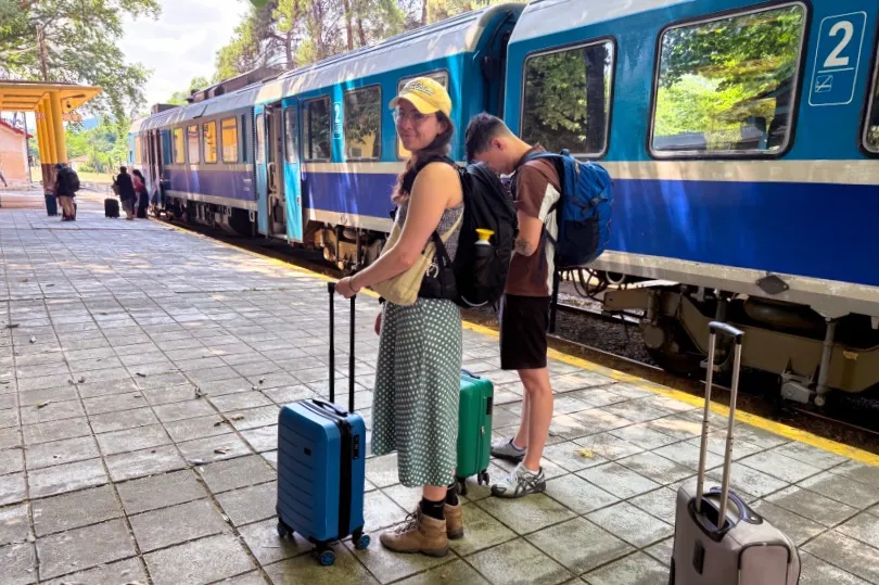 Twee mensen staat met koffer naast de trein naar Griekenland te wachten.