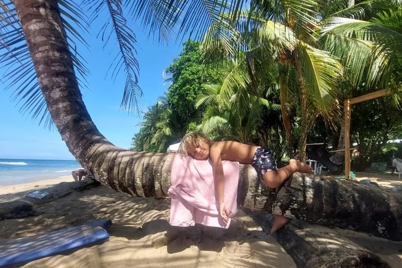 Jongetje ligt op een palmboom  op het strand in Costa Rica