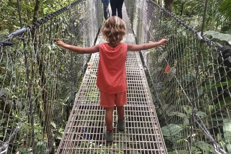Jongetje loopt op een brug in het woud van Costa Rica