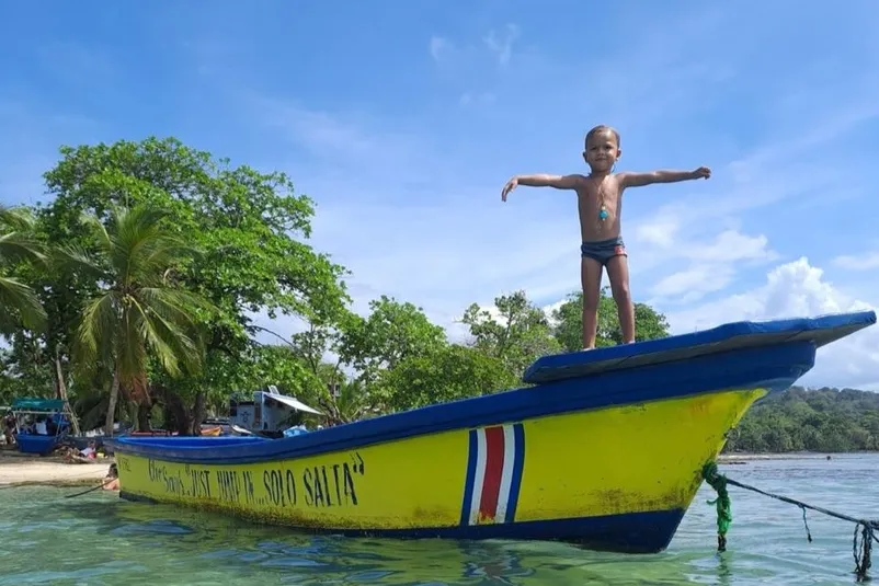 Jongetje staat op de voorkant van een kleine boot in de zee van Costa Rica