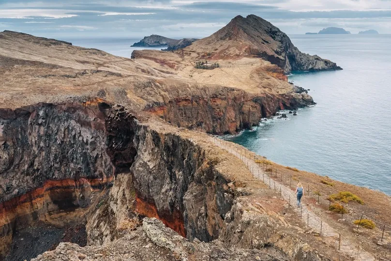 Een ruig kustpad slingert over de vulkanische kliffen van Ponta de São Lourenço, met uitzicht op de azuurblauwe oceaan van Madeira.