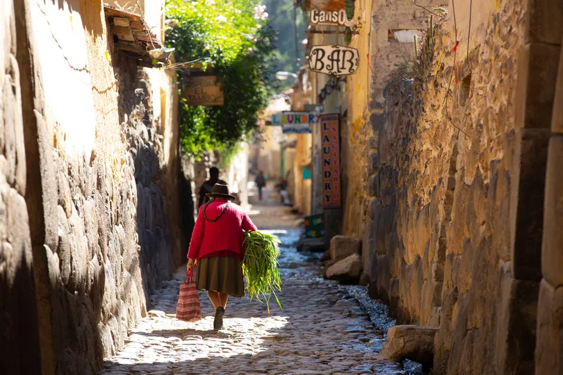 Vrouw loopt door straatje in Ollantaytambo in Peru.