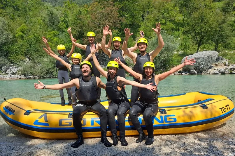 8 persoenen, jong tot oud zitten heel blij juigende te poseren voor een foto voor het raften.