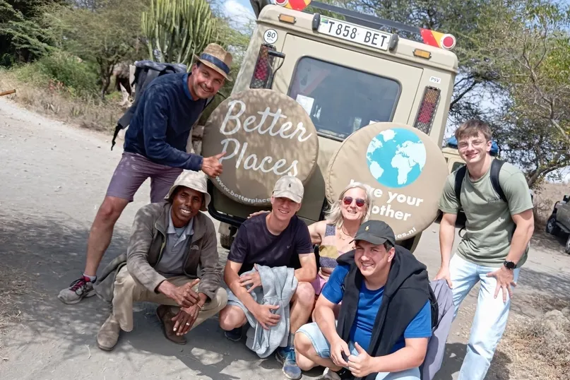 6 personen gehurkt voor een safari auto van Better Places in Tanzania