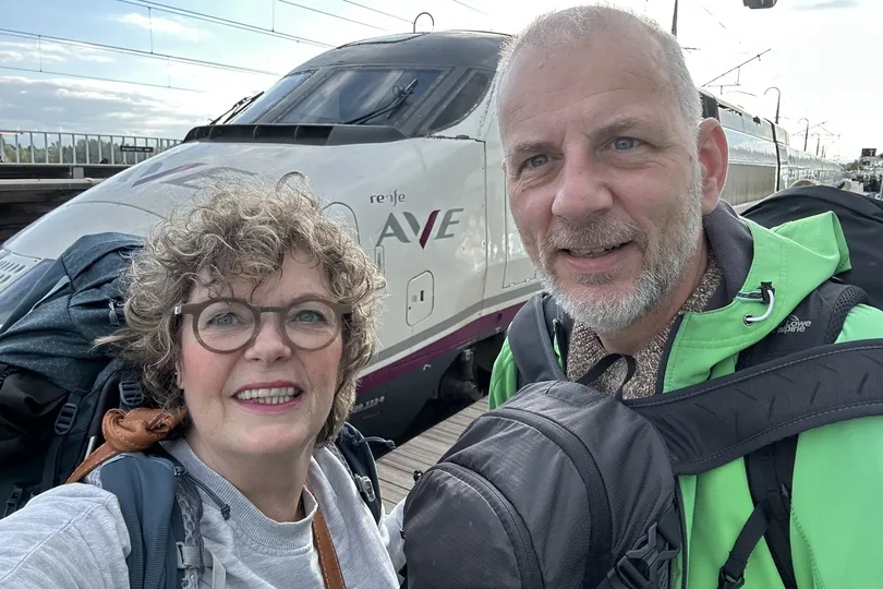 Twee reizigers maken een foto voor de trein.