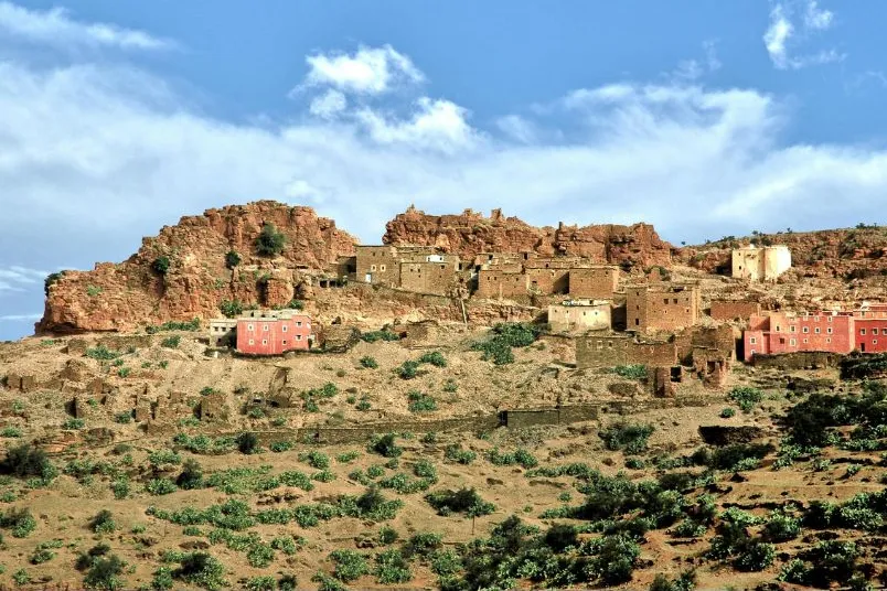 Een dorp met zandkleurige huizen vlakbij de woestijn met wat groene struiken.