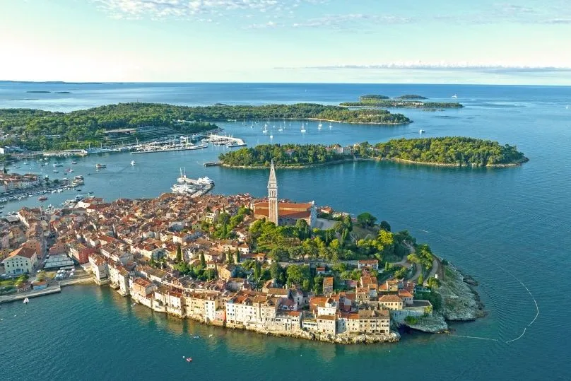 Een eiland met heel veel gebouwen, een kerk en bomen met daaromheen nog een paar kleine eilanden. 