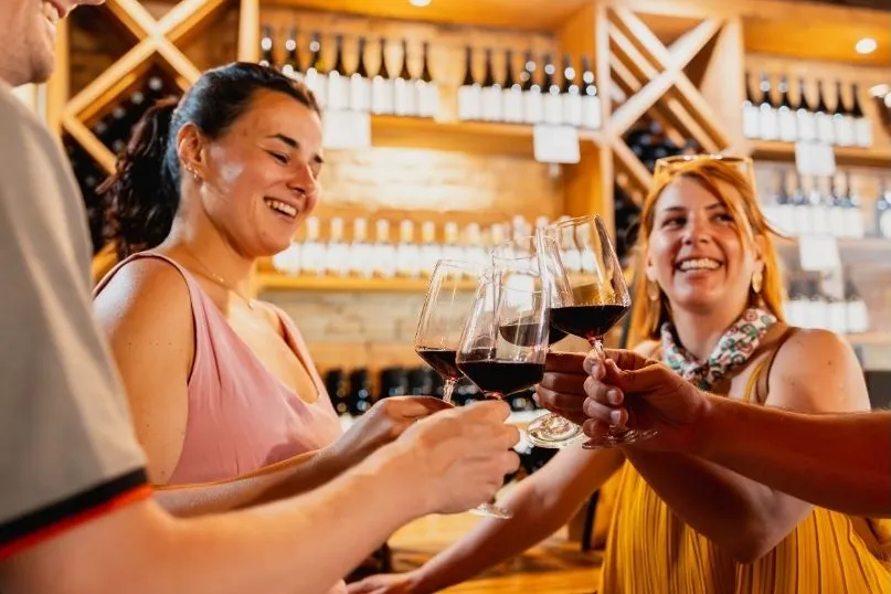 4 mensen die proosten met een rood glas wijn.