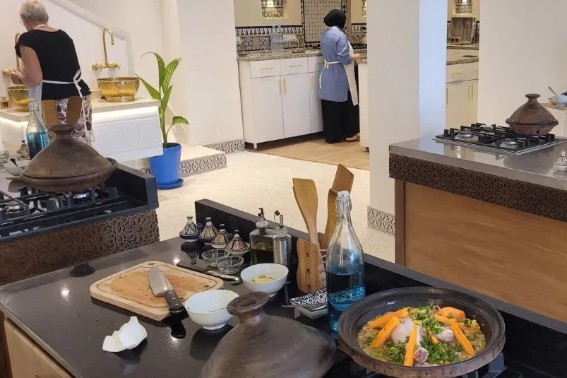 Een grote keuken met 2 vrouwen die aan het koken zijn bij het aanrecht. 