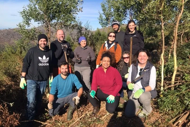 10 mensen die een groepsfoto maken tussen de bomen. 