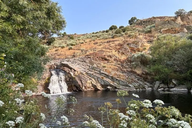 Een meer met een kleine waterval uit een heuvel.