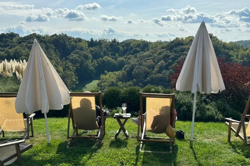 Twee mensen die op een klapstoeltje van het uitzicht en de natuur genieten met een glas witte wijn. 