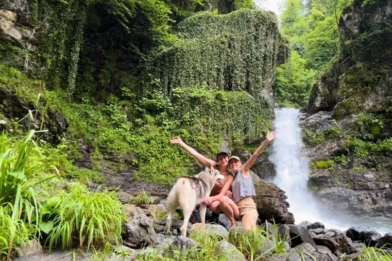 twee reizigers poserende meteen hond voor een waterval.