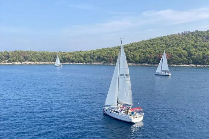 3 zeilboten op het water vlakbij de kust.