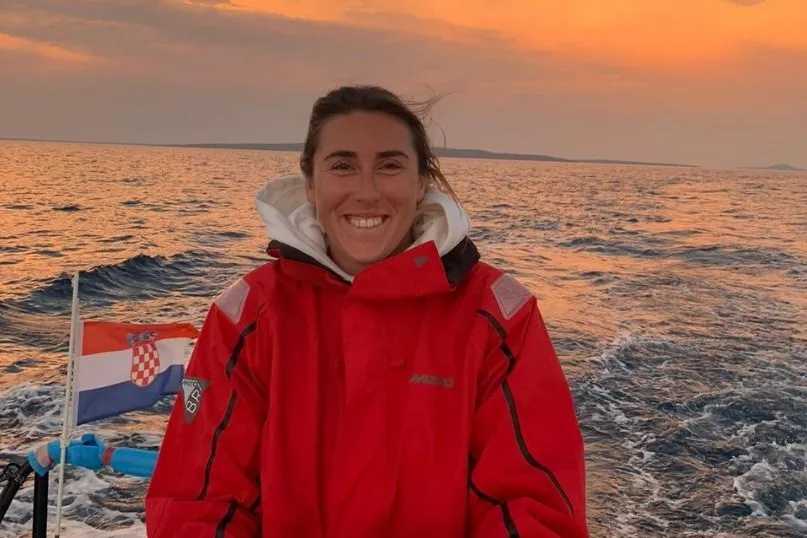 Reisexpert Melissa in een rode jas op een bootje op de zee. 