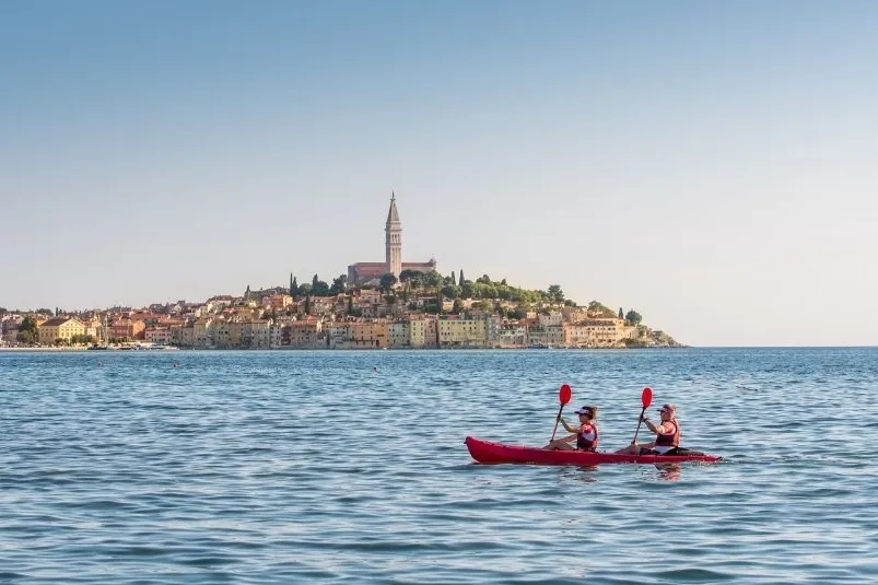 2 mensen in een kajakboot naast een eiland in de zee.