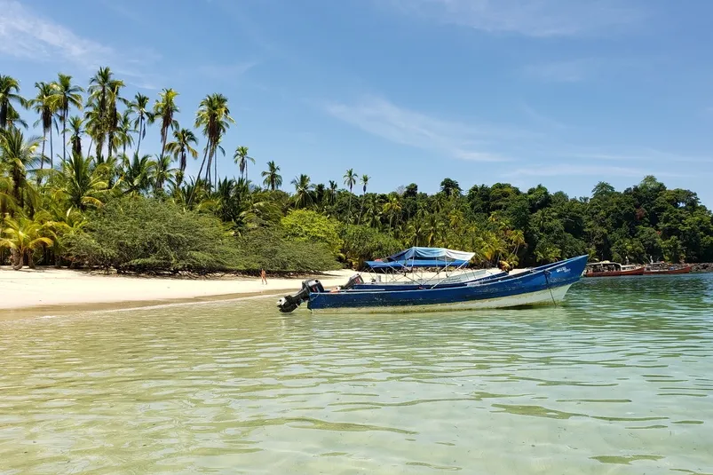 Panama - strand met helderblauw water en bootje in Coiba.