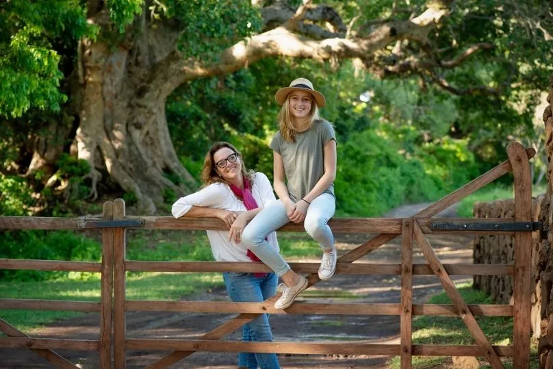 De reisexpert van Tanzania met haar dochter zittende op een hekje. 