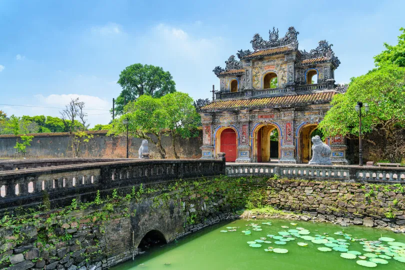 Historische stadspoort in Hue, met een stenen brug over een gracht met waterlelies.