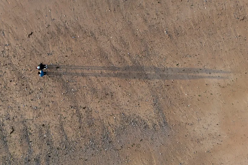 Strand van Courseulles-sur-Mer, een stel bij zonsondergang met schaduwen op het zand, luchtfoto.