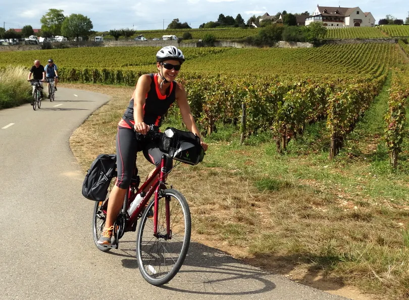 Fietsers die de bocht doorkomen op de fiets op een rustig landweggetje in Frankrijk langs rijen met wijngaarden.
