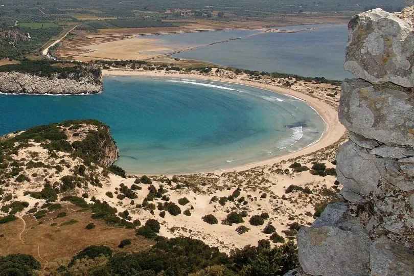 Baai met helderblauw water en een breed zandstrand.