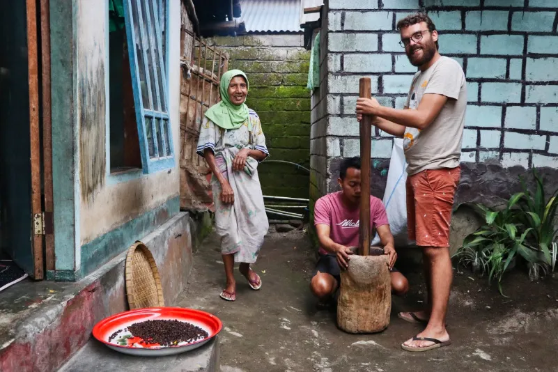 Reiziger met locals bij een homestay in Lombok bezig met koffiebranden.