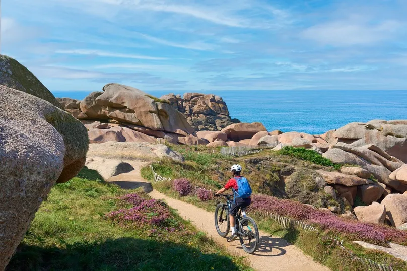 Reiziger die door de granietkust van Bretagne fietst.