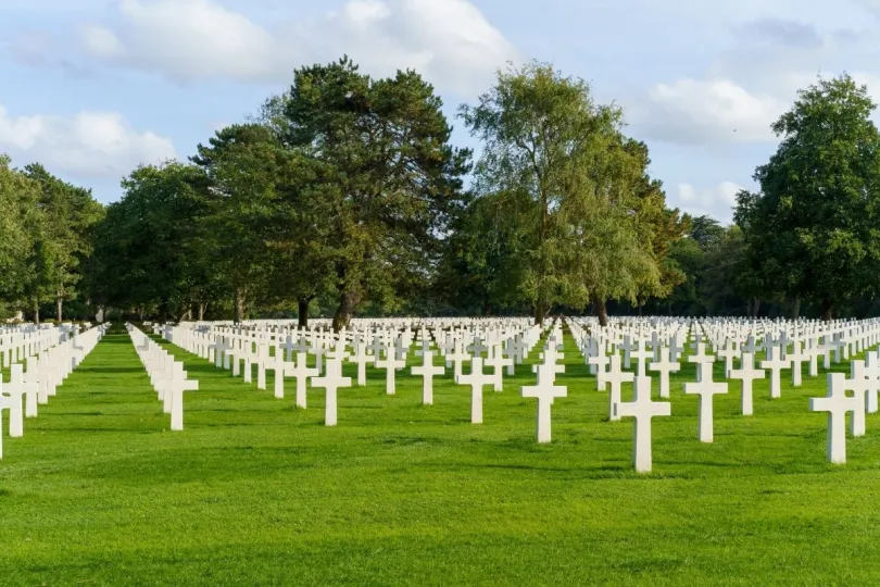 Rijen witte kruizen staan op een grasveld en vormen de Amerikaanse begraafplaats in Colleville-sur-Mer, Normandië.