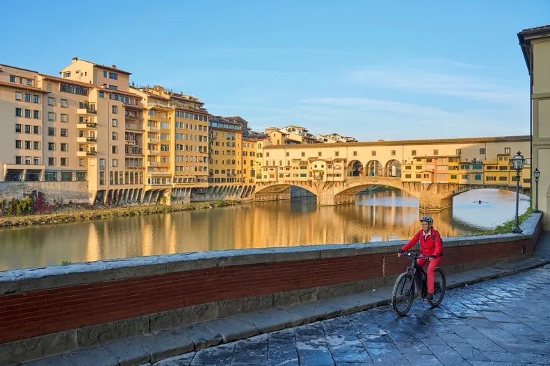 Fietser in Florence met Ponte Vecchio brug op de achtergrond.