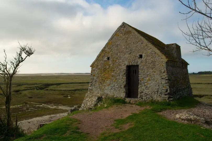 Een klein stenen huisje op een groene heuvel in een moerasachtig landschap in Normandië, Frankrijk