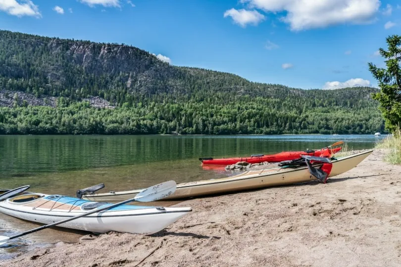 3 kajaks liggen aan de kant van een helder meer in Zweden.
