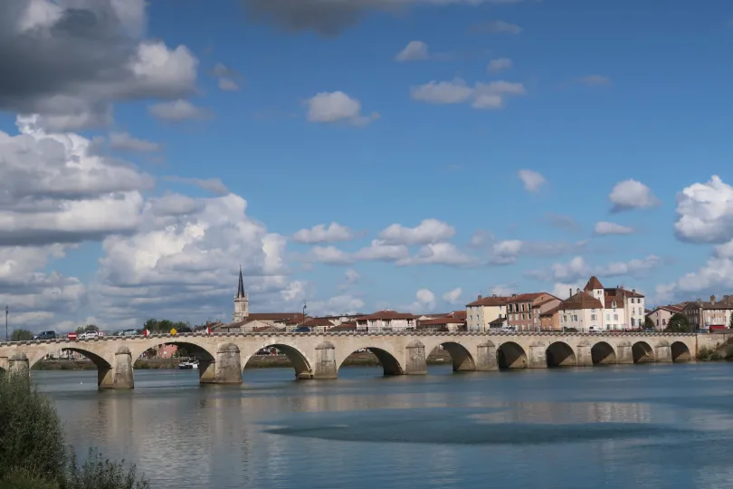 Uitzicht op de Saint-Laurent brug bij de stad Mâcon in Frankrijk over rust water met daarachter de stad met gebouwen en een kerk.