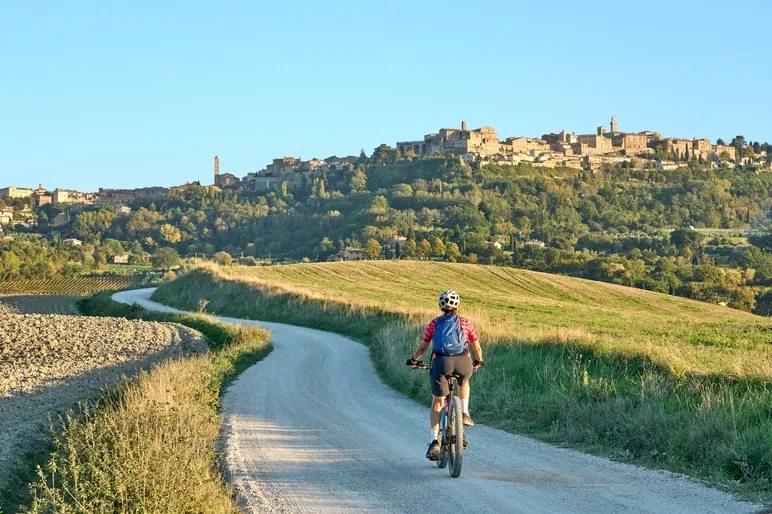 Fietser op een weg met gebouwen op de achtergrond in Montepulciano, Toscane.