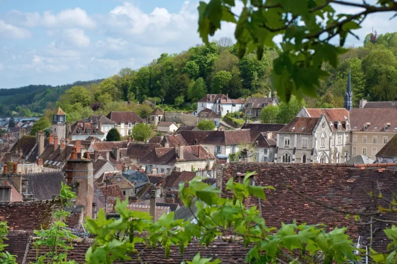 Uitzicht op Tonnerre in Bourgogne met huisjes tussen de groene heuvels en omringt door bomen met een kerkje die erboven uit komt. 