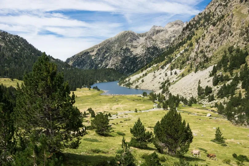 Een bergmeer ligt tussen groene valleien en rotsige toppen in de Pyreneeën.