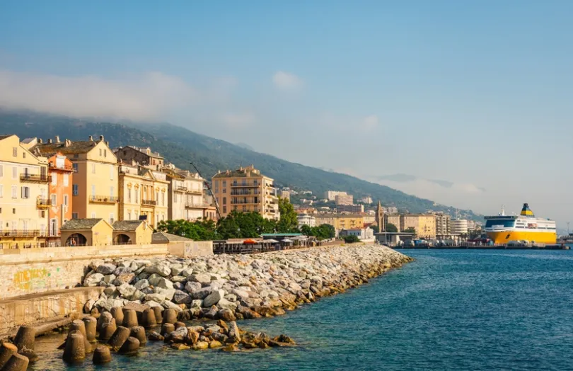 Corsica, Bastia: panoramisch uitzicht op de haven van Porto Vecchio op het eiland Corsica, Frankrijk. De oude haven met kleurrijke gevels langs de kustlijn en een gele veerboot vormt een sfeervol geheel.