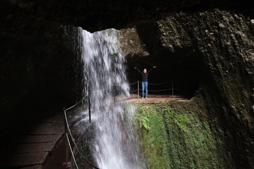 Kind staat achter een waterval tijdens een wandeling op Madeira