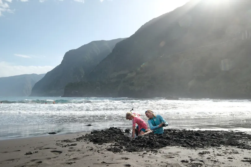 Kinderen spelen op een zwart zandstrand aan de kust van Madeira