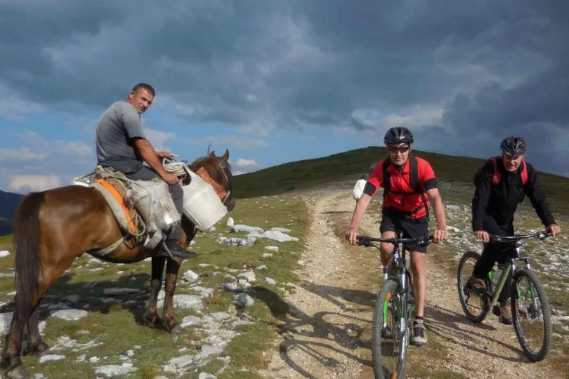 Twee mountainbikers en een herder op een paard in Montenegro.