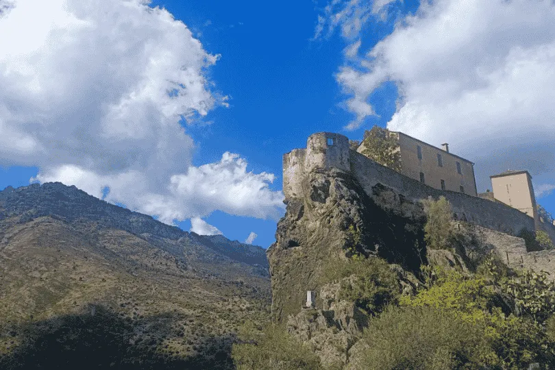 Citadel van Corte boven op een rots met bergen op de achtergrond.