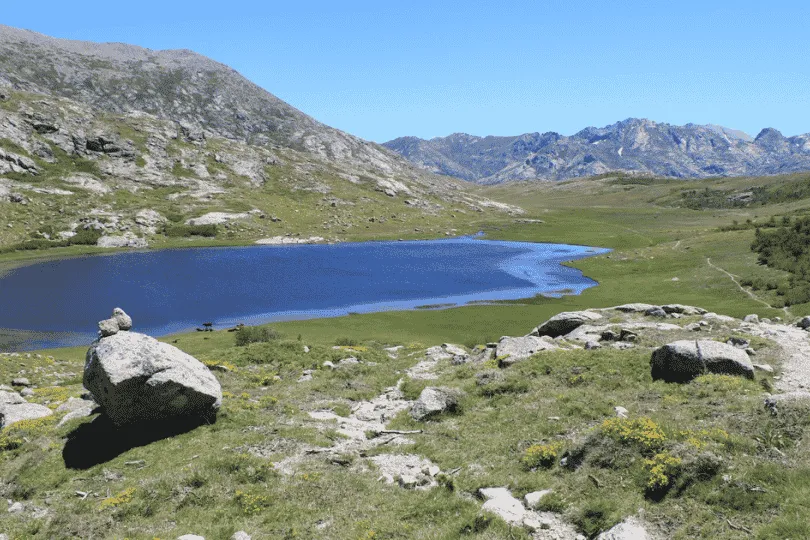 Bergmeer tussen groene valleien en rotsachtige bergtoppen.