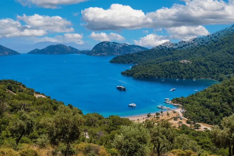 Uitzicht over een helderblauwe baai bij Dalaman, omringd door groene heuvels en beboste bergen.
